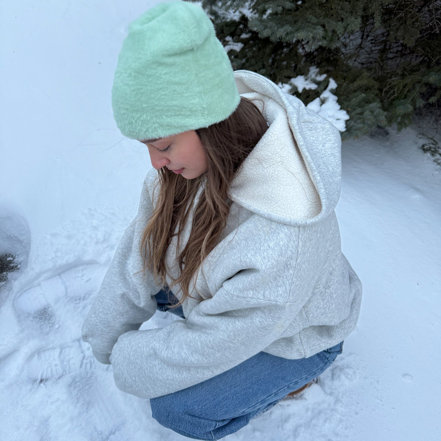 
                  
                    Portrait of a women wearing a soft mint green faux fur hat and a winter jacket outdoors.
                  
                